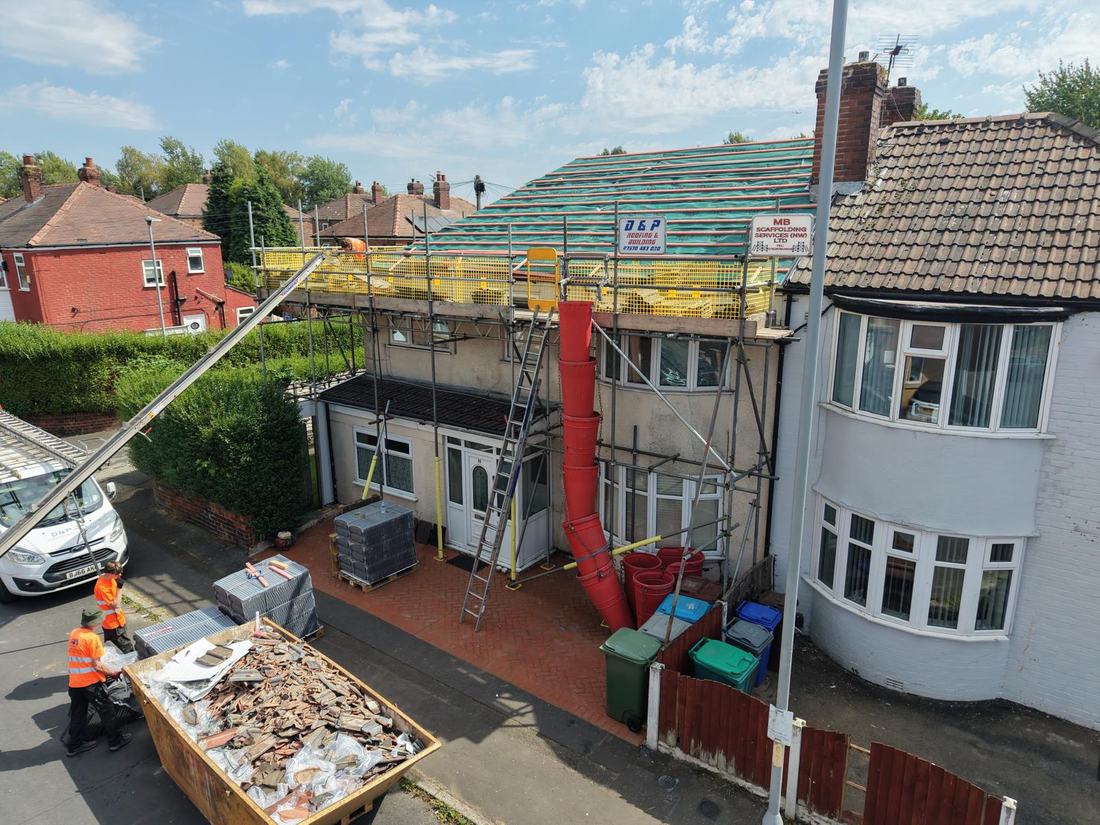 The D & P team on scaffold laying felt and battens on a re-roof, with a skip below